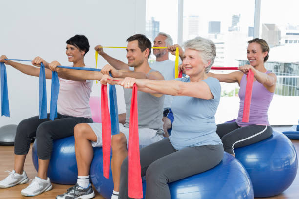 istock Class holding out exercise belts while sitting on fitness balls 693085476