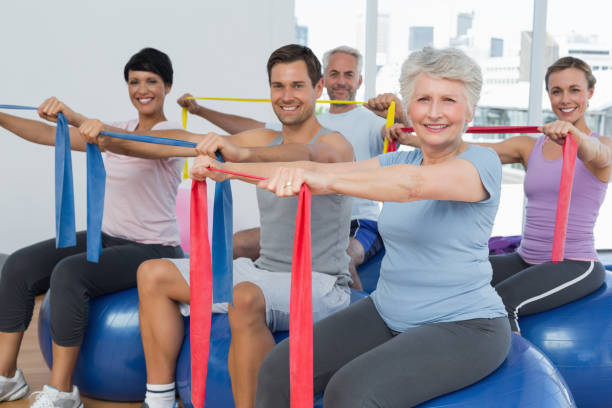 istock Class holding out exercise belts while sitting on fitness balls 693087898