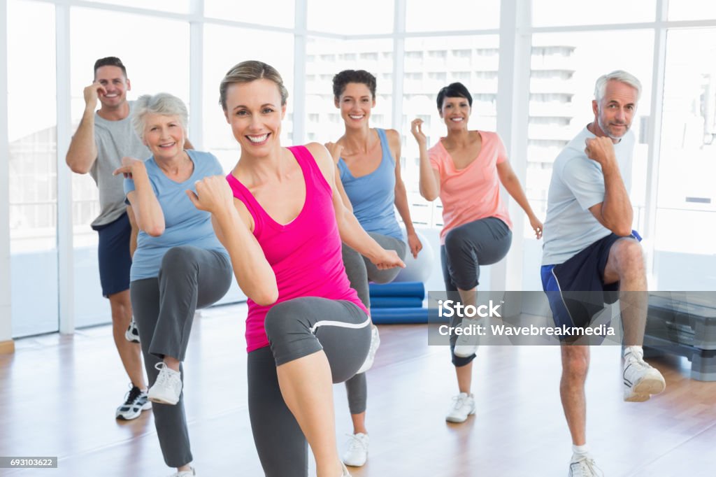 Smiling people doing power fitness exercise at yoga class Portrait of smiling people doing power fitness exercise at yoga class in fitness studio Aerobics Stock Photo