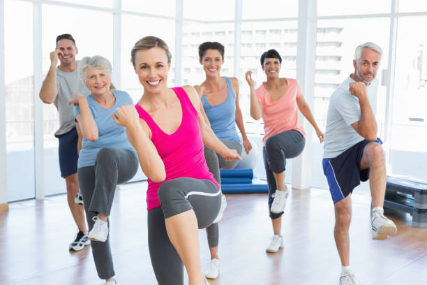 Smiling people doing power fitness exercise at yoga class Portrait of smiling people doing power fitness exercise at yoga class in fitness studio aerobics photos stock pictures, royalty-free photos & images