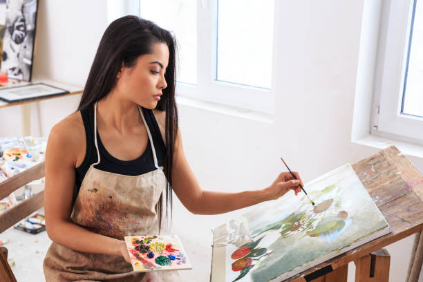 istock Prifile view of female painter working in her studio 693125496