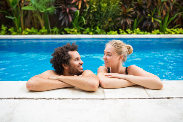 istock Smiling Couple Resting at Edge of Swimming Pool 693125834