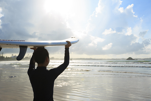 young woman surfer with surfboard ready to surf on a beach
