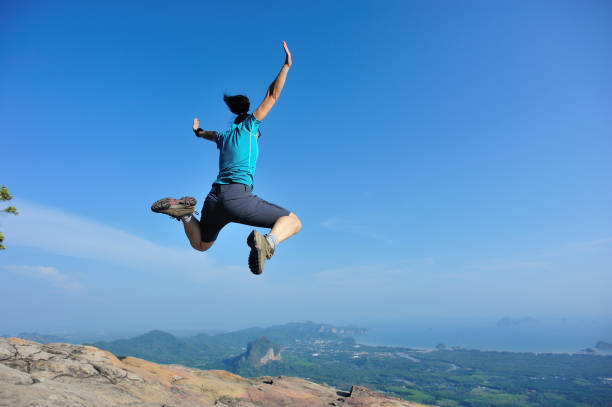 istock successful woman jumping on rocky mountain peak 693147848