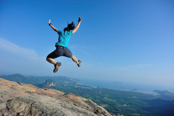 istock successful woman jumping on rocky mountain peak 693147976