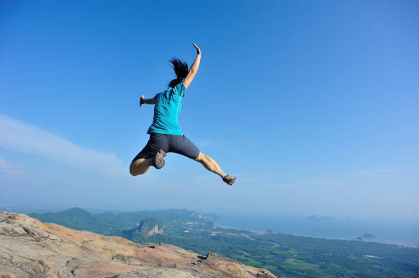 istock successful woman jumping on rocky mountain peak 693148098