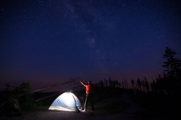 istock Tourist with flashlight near his camp tent at night 693148846