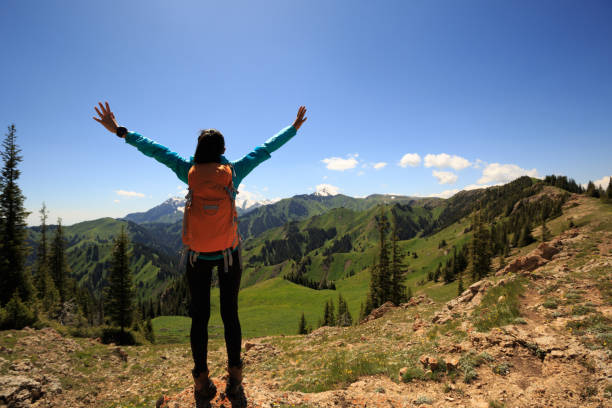 istock Cheering young woman hiker open arms on mountain top 693155188