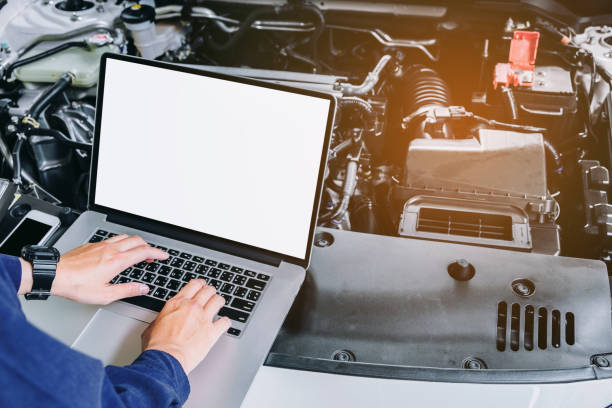 istock Professional car mechanic working in auto repair service using laptop on car 693169688