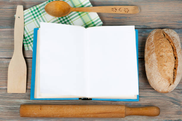 istock Open recipe book on wooden background, spoon, rolling pin , green checkered tablecloth 693175366