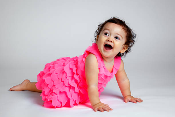 Young girl on a white background, looks up and smiles as she is passes.  Her eyes are big and bright and her mouth is wide open.  She looks excited.