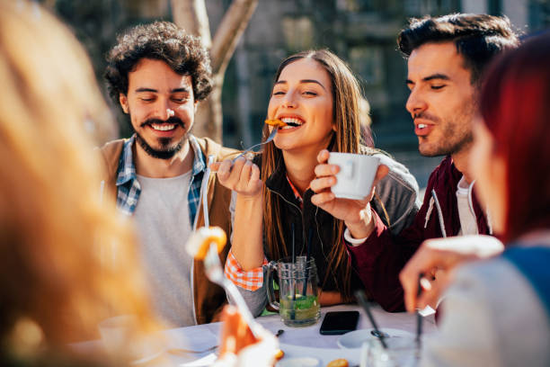 Friends eating at a restaurant Friends eating and having drinks at a restaurant. mouth full stock pictures, royalty-free photos & images