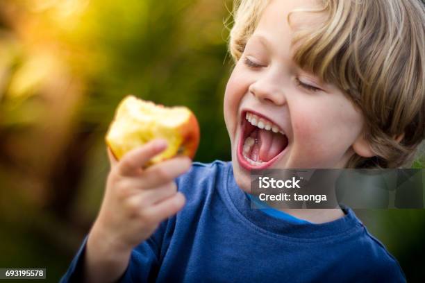 Cute Blonde Child About To Take A Bite Of An Apple Stock Photo - Download Image Now - Child, Eating, Apple - Fruit