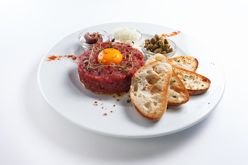Beef tartar with egg yolk. Isolated on white.