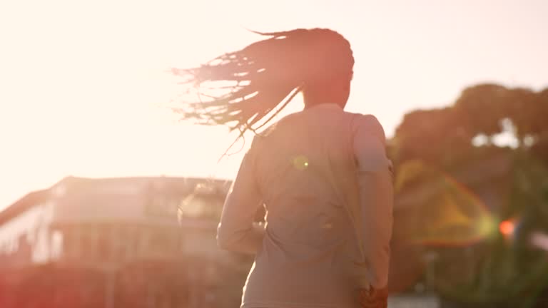 SLO MO African-American woman with long braided hair running in the stadium at sunset