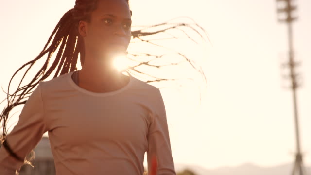 SLO MO DS African-American female athlete running in the sunny stadium at sunset