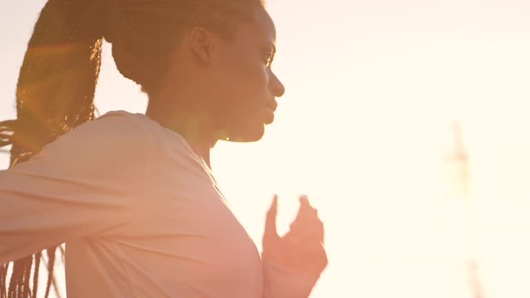 SLO MO TS African-American woman with braided hair running at sunset