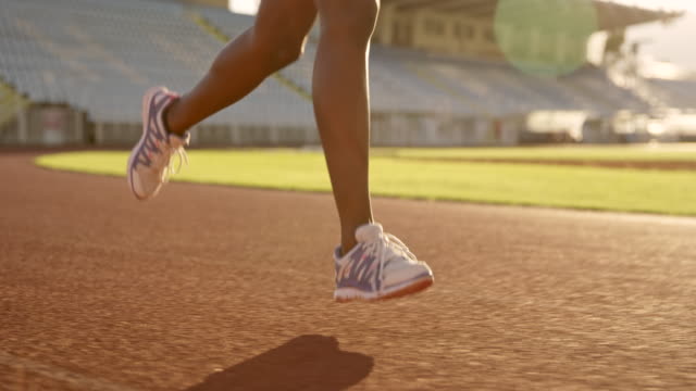 SLO MO TS Legs of an African-American woman running in stadium at sunset