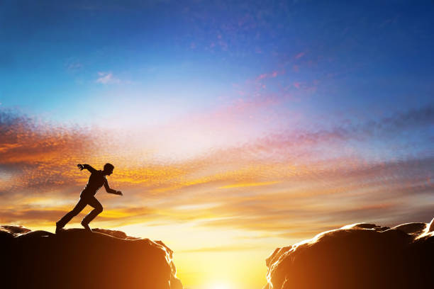 Man running fast to jump over precipice between two mountains. Challenge