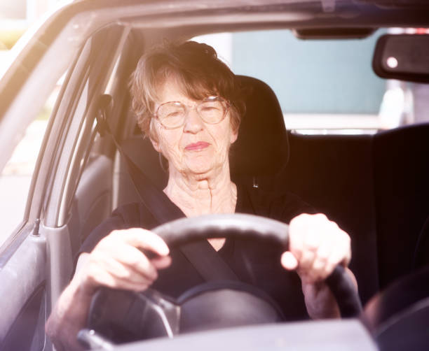 istock Old woman driving car smiles confidently 693210162