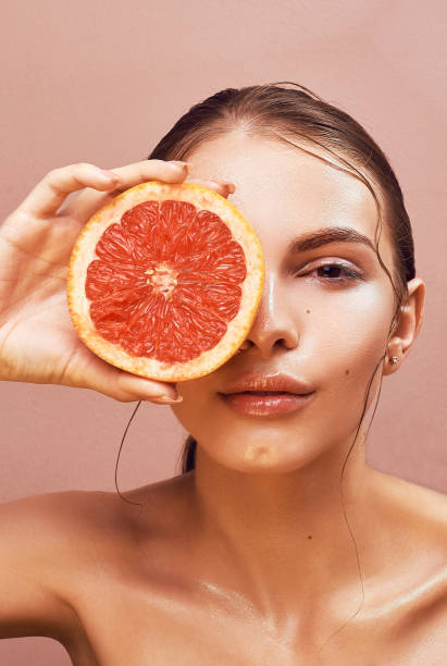 istock Sensual young woman with bright makeup holding delicious grapefruit in her hand 693227220