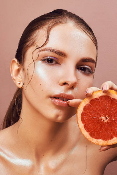 istock Sensual young woman with bright makeup holding delicious grapefruit in her hand 693227260