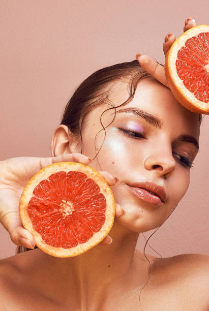 istock Sensual young woman with bright makeup holding delicious grapefruit in her hand 693227262