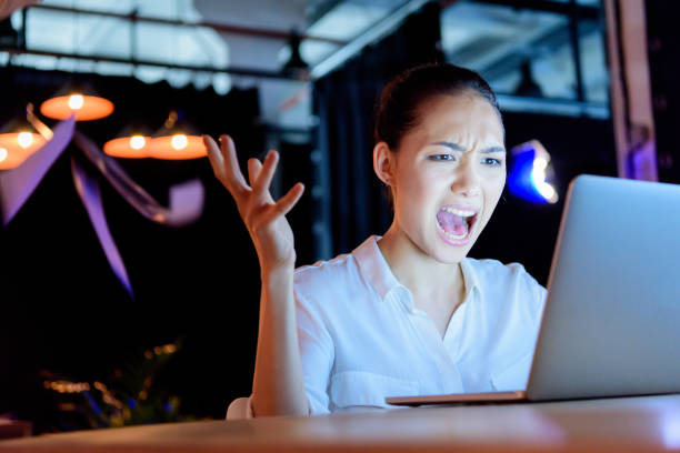 istock businesswoman yelling while looking at laptop with gesture 693227390