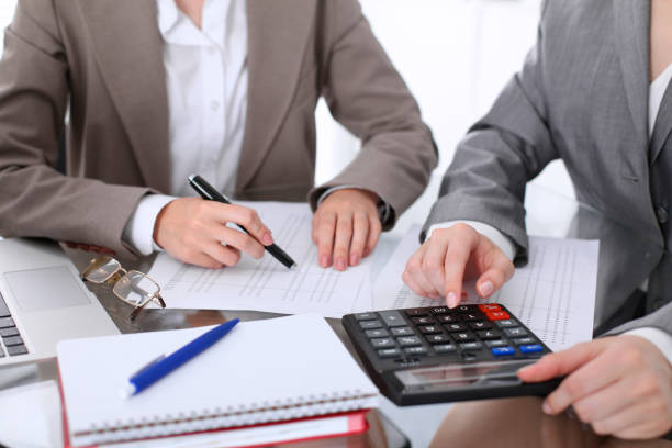 Two female accountants counting on calculator income for tax form completion hands closeup. Internal Revenue Service inspector checking financial document. Planning budget, audit concept. dos contadores mujer contando con ingresos de calculadora para impuestos forman closeup de las manos de terminación. inspector de servicio de impuestos interno comprobación de documento financiero. planificación presupuesto, concepto de auditoría