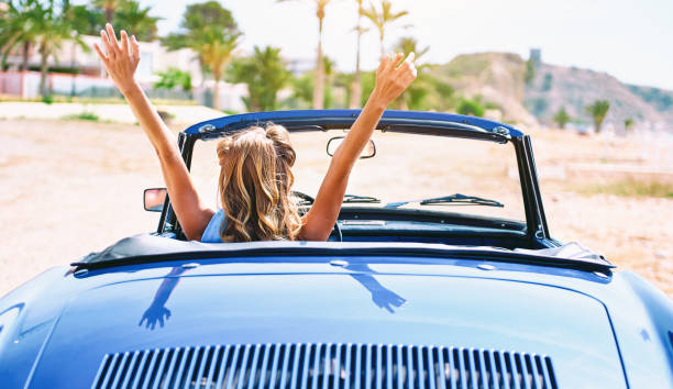 woman sitting in retro cabriolet car. back view - image created 1960s 1960s style beach women imagens e fotografias de stock