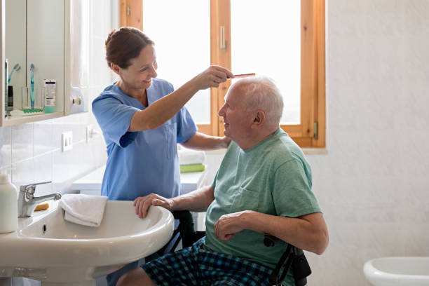 Home Caregiver with senior man in bathroom Home Caregiver with senior man in bathroom personal care aid stock pictures, royalty-free photos & images