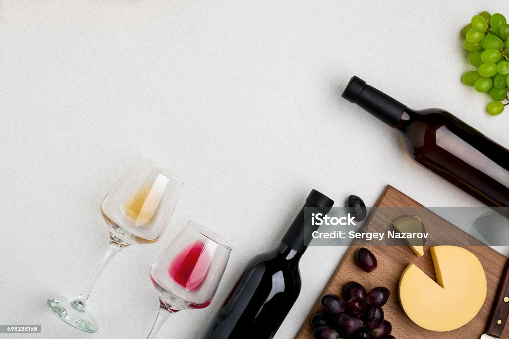 Two wine glasses with red and white wine,bottles of red wine and white wine, cheese on white background. Horizontal view from the top Two wine glasses with red and white wine,bottles of red wine and white wine, cheese on white background. Horizontal view from the top. Mock-up. Copy space. Flat lay Wine Stock Photo