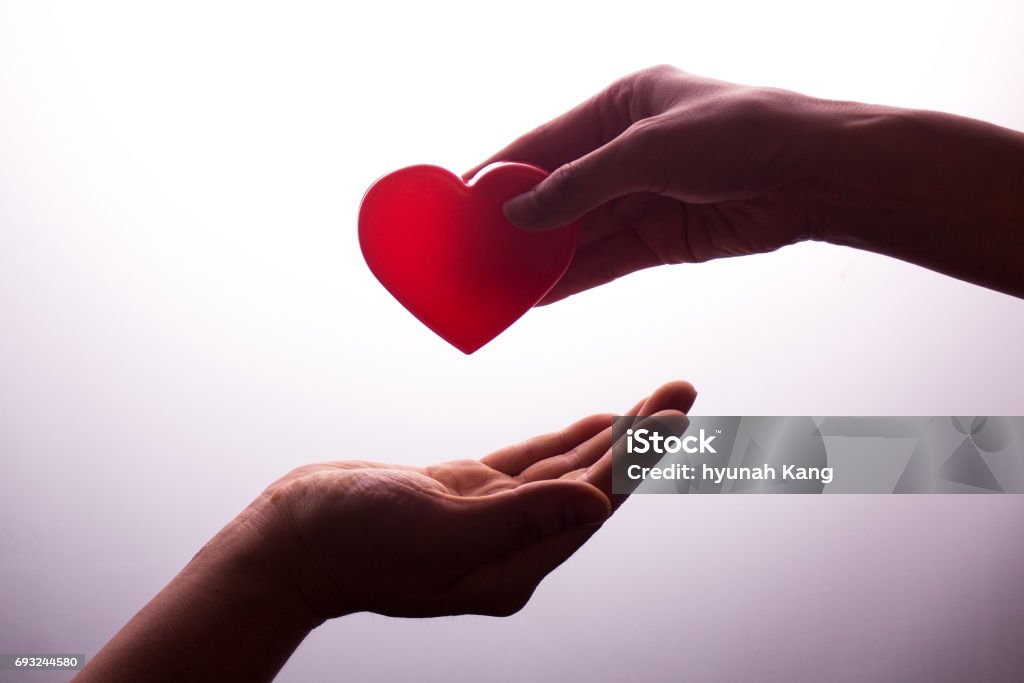 A hand gives a red heart to a hand - blood donation,world blood donor day Organ Donation Stock Photo