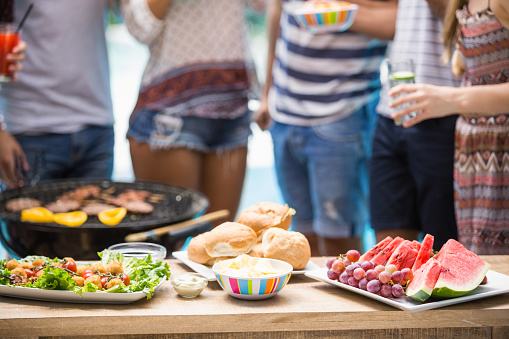 Table laid with hamburgers, fruits and barbecue for outdoors barbecue party