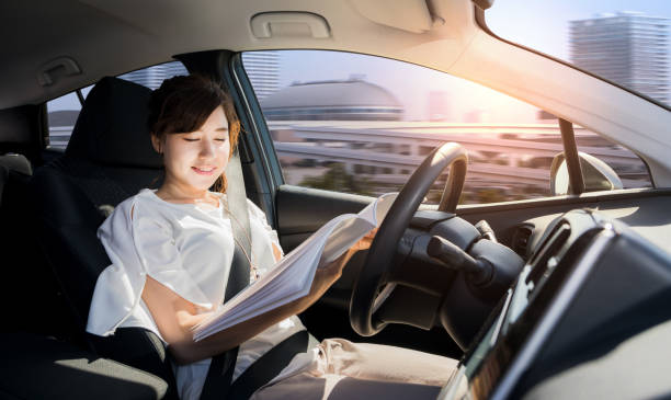 mujer joven leyendo una revista de coches autónomas. mismo vehículo. piloto automático. tecnología automotriz. - automóvil sin conductor fotografías e imágenes de stock