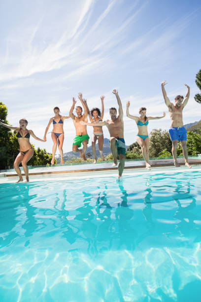 Happy Teenagers Jumping Into An Outdoor Pool Vertical Stock Photos ...