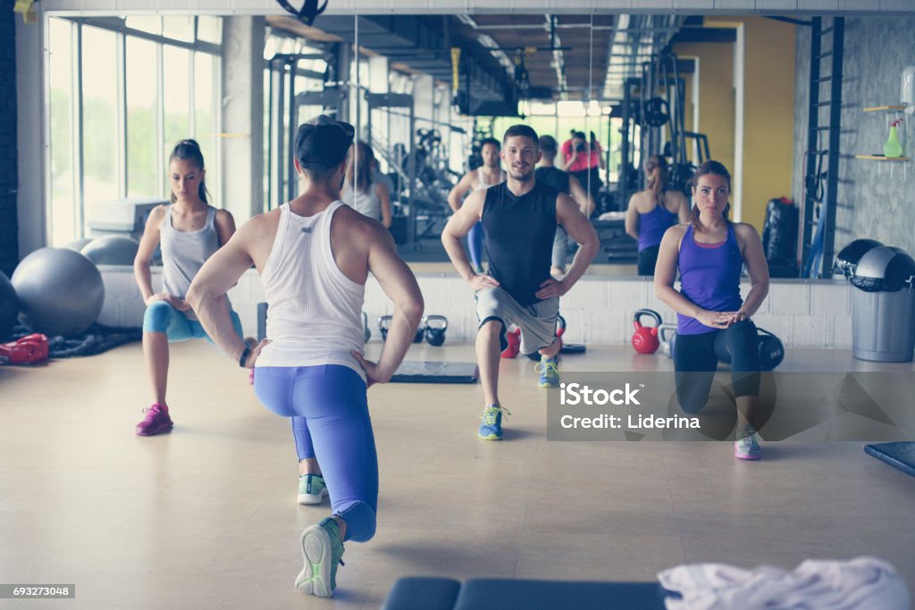 Group of people workout in healthy club. Young people stretching for legs. Fitness Instructor Stock Photo