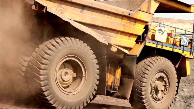 A large tipper digs through a career, an industrial truck dredges cargo in its quarry, a large yellow dumper