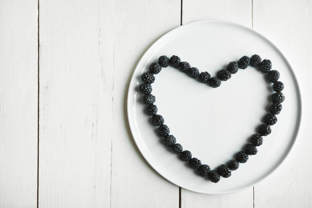 High angle shot of blackberries in the shape of a heart on a plate