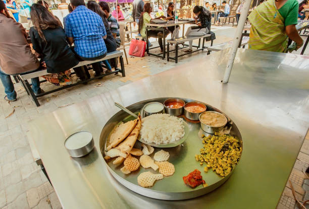 студенты едят индийские вегетерианские продукты питания тали в кафе на открытом воздухе - vegeterian food стоковые фото и изображения