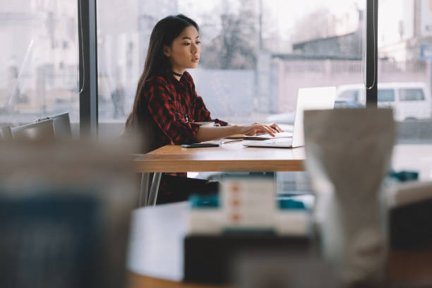 istock attractive brunette asian girl using laptop computer in cafe 693279928
