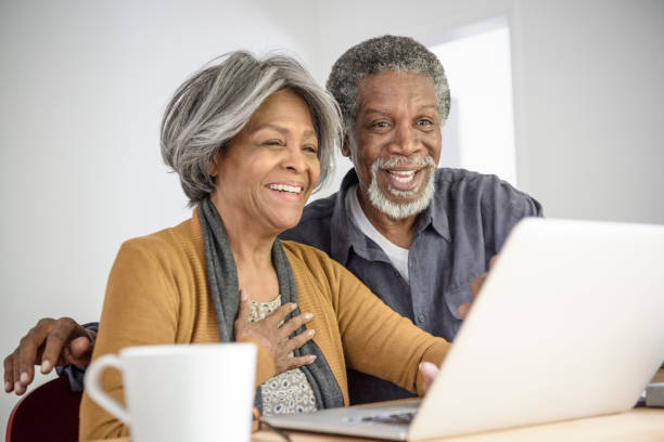 alegre casal sênior afro-americano, usando laptop, sorrindo - hand on heart - fotografias e filmes do acervo