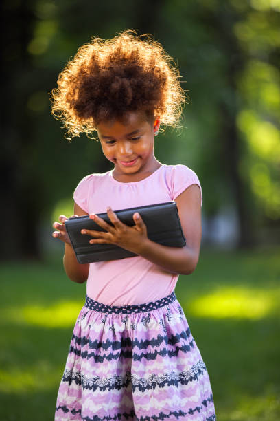 istock Adorable little girl using digital tablet outdoors 693294610