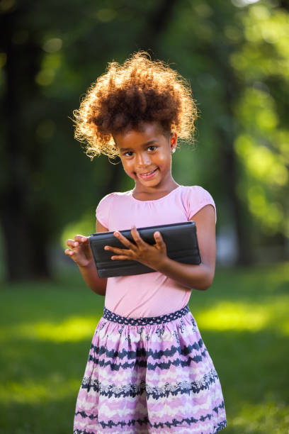 istock Adorable little girl using digital tablet outdoors 693300926