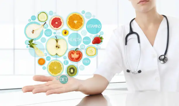 Photo of healthy food supplements concept, Hand of nutritionist doctor showing symbols fruits in hearth shape