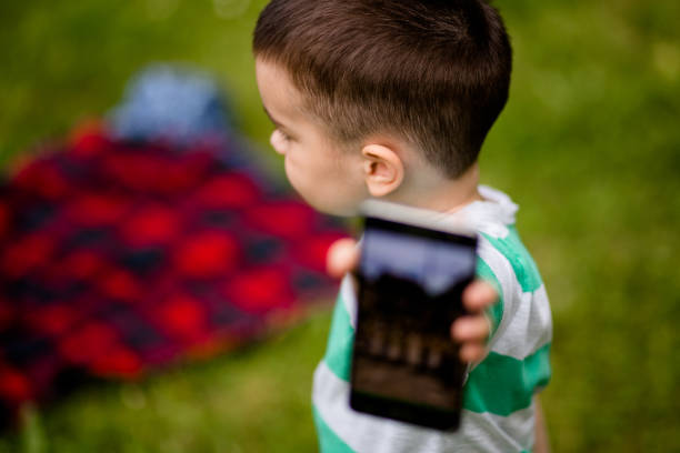 istock Boy Gesturing With His Mobile Device On Summer Day Outdoors 693310934