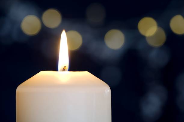 istock Burning candle against blue background with golden bokeh 693311662