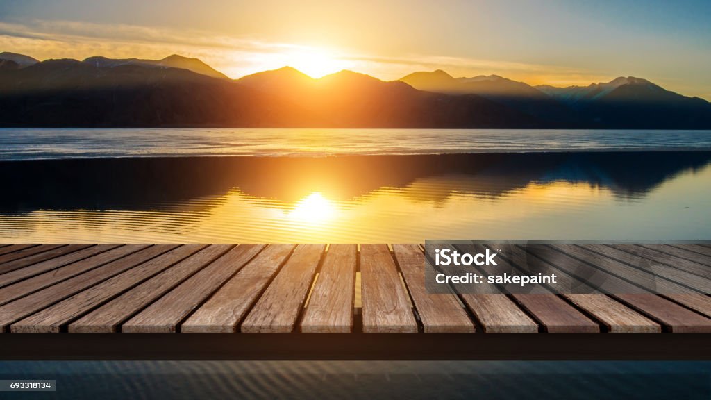 Ponte di legno sul lago con un riflesso del tramonto sulla montagna di neve - Foto stock royalty-free di Tramonto