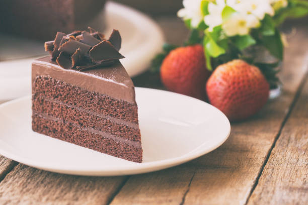 istock Homemade bakery: chocolate fudge cake decorated with chocolate curl. Triangle slice piece of chocolate cake on rustic wood table for cafe,meeting, coffee break or tea time and birthday party. 693321996