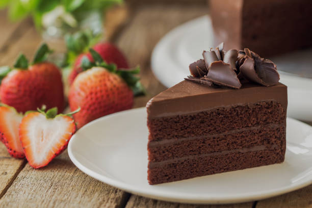 istock Homemade bakery: chocolate fudge cake decorated with chocolate curl. Triangle slice piece of chocolate cake on rustic wood table for cafe,meeting, coffee break or tea time and birthday party. 693322830